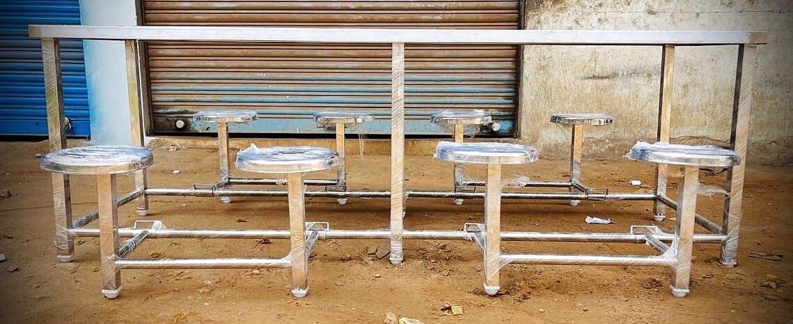 Front view of an 8 seater SS dining table with four stools on each side