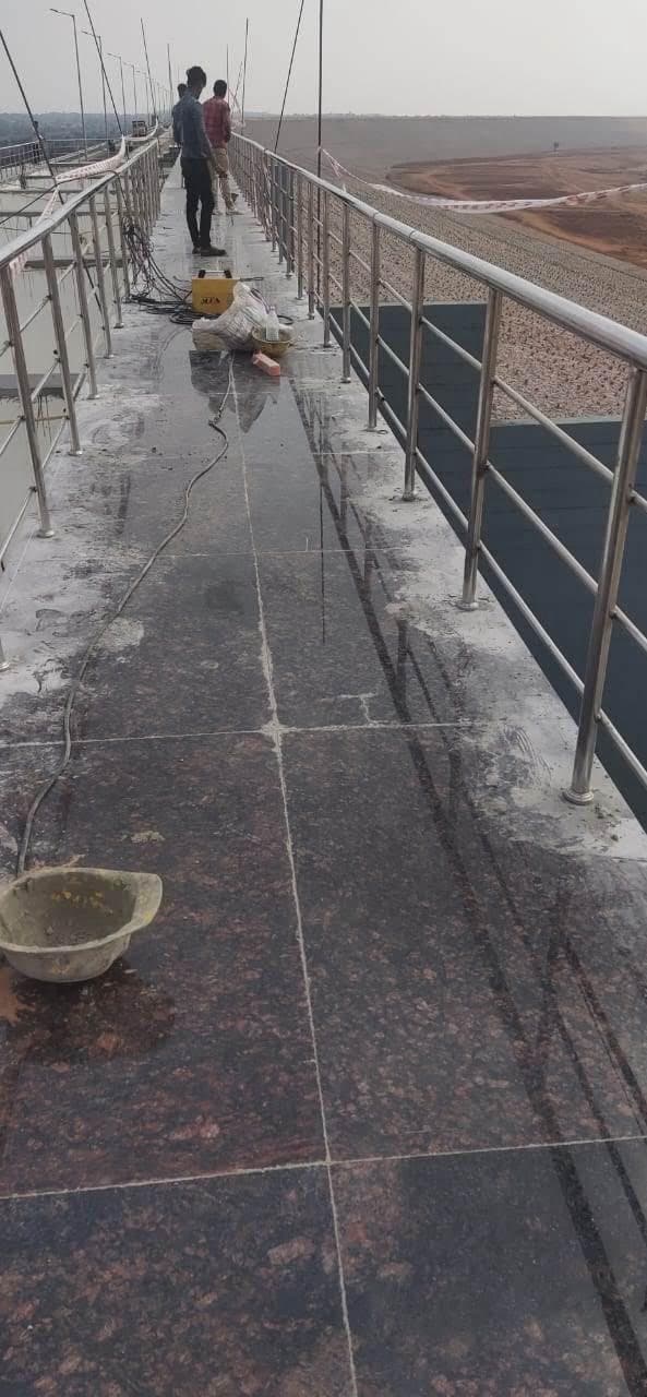 Narrow bridge walkway with stainless steel railing on both sides and welding equipment